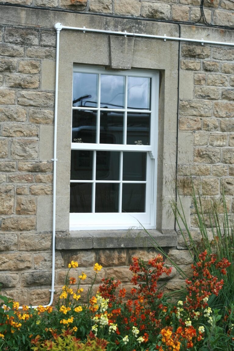 White uPVC sash and case window in a stone wall
